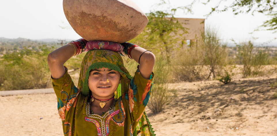 Young girl carrying a water pot on her head