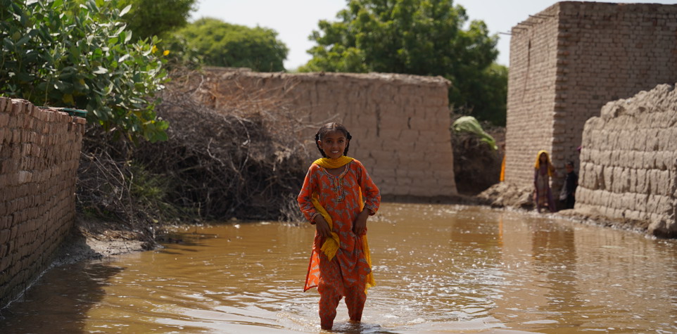 A litttle girl walking in a flooded street